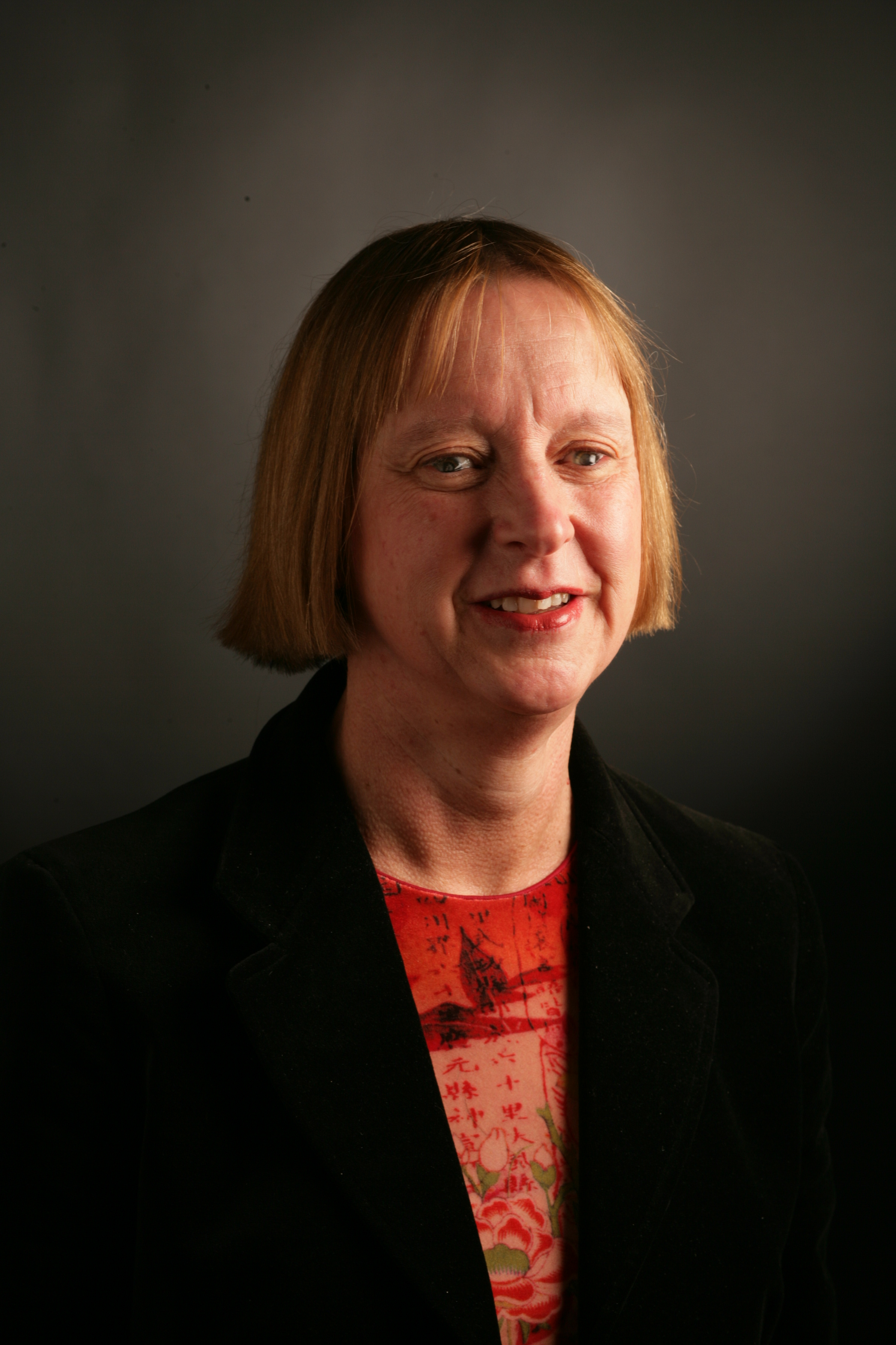 Mary, a Caucasian woman with a blonde bob haircut, poses for a professional headshot, smiling softly towards the right of the frame.